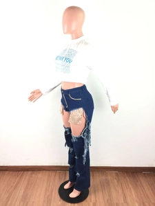 Detail of high-waist distressed jeans with large cut-outs and gold sequin pocket lining
