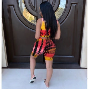 Detail of red and yellow tie-dye biker shorts and crop top on model against wooden door