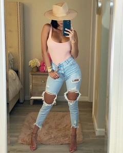 Body rose moulant avec un jean déchiré à taille haute bleu clair et un chapeau beige