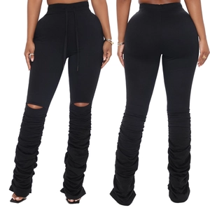Détail du pantalon noir empilé avec découpes aux genoux et taille à cordon