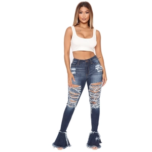 Detail of distressed high-waisted denim jeans with large knee cutouts and flared frayed hems