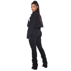 Détail de l'ensemble pantalon froncé noir slim et veste courte sur fond blanc