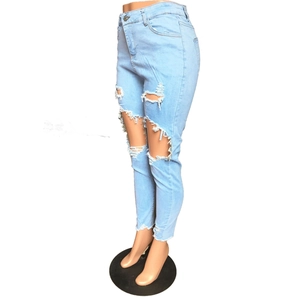 Détail de l'effet usé déchiré et de l'ourlet effiloché sur un jean slim bleu clair