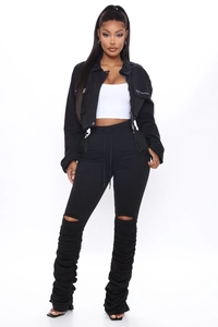 Détail du pantalon empilé noir avec genoux déchirés et design plissé style urbain
