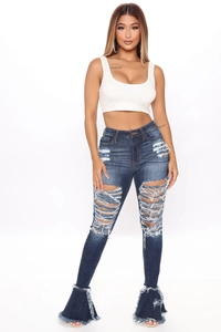 Detail of dark blue high-waisted flare jeans with ripped holes and fringe hem design