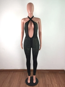 Dettaglio della tuta nera allacciata al collo con profondo scollo a U e strass argentati