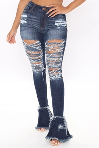 Detail of high waisted blue flared jeans with ripped holes and fringe hem design