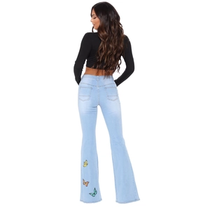 Détail de la broderie papillon colorée sur le jean évasé bleu clair à coupe ajustée