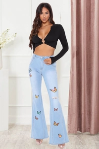 Détail du jean évasé taille haute bleu clair avec broderies papillon colorées et déchirures