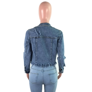 Detail of ripped distressed blue denim jacket back with frayed edges and retro sleeve style