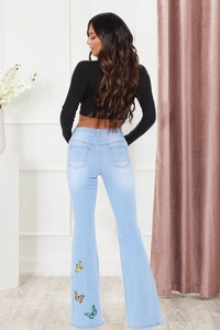 Vue arrière du jean évasé bleu clair avec broderies papillons colorées sur la jambe