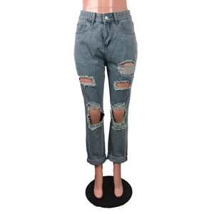 Dettaglio dei jeans blu strappati con baffature e orli risvoltati esposti su un manichino