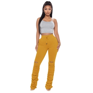 Détail du pantalon froncé jaune à taille haute avec fentes aux genoux et plis bas