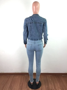 Rear view of blue denim jacket with distressed details and frayed hemline on a mannequin