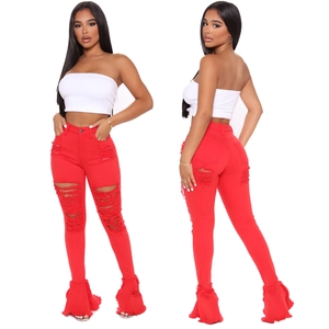 Detail of red distressed flare jeans with frayed edges and ripped knees design