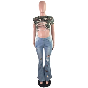 Détail d'un crop top camouflage déchiré et d'un jean évasé avec broderie papillon