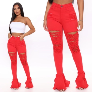 Detail view of red high-waisted distressed bell-bottom jeans with frayed ruffle hems