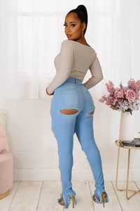 Détail du jean skinny taille haute avec déchirures sous les poches et ourlet à franges