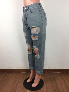 Dettaglio di jeans strappati azzurri con tessuto consumato e orli risvoltati alla caviglia
