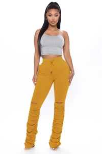Détail du pantalon froncé en jaune moutarde avec découpes tendance aux genoux et cordon