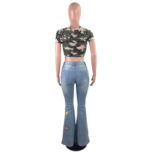 Détail du jean évasé taille haute avec broderie papillon et haut court à motif camouflage