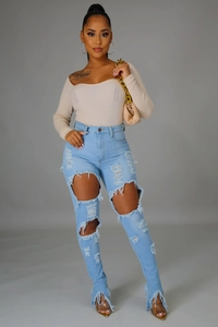 Détail du jean denim taille haute avec ourlets effilochés et grandes déchirures stylisées