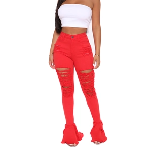 Detail shot of women's red flare jeans with ripped knee design and frayed ruffled hem