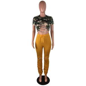Détail du crop top camouflage ajouré et du pantalon froncé jaune moutarde avec déchirures