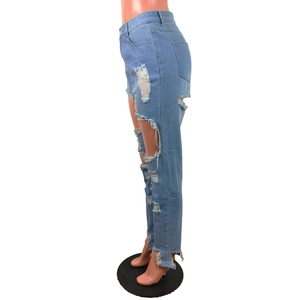 Détail d'un jean bleu clair délavé montrant des déchirures et des bords effilochés