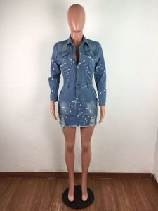 Detail of blue denim dress featuring white paint splatters and distressed frayed hemline