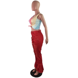 Detail view of red flared denim pants with frayed holes and double ruffled hemline