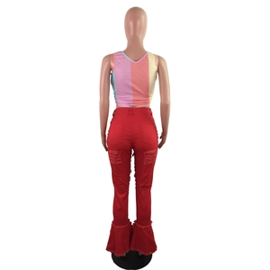 Detail of red flared jeans with distressed cut-outs and colorful striped knit tank top