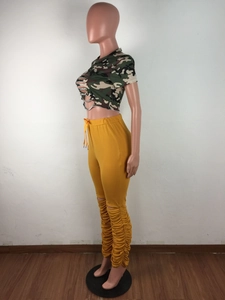 Détail du crop top camouflage et pantalon jaune froncé avec déchirures aux genoux