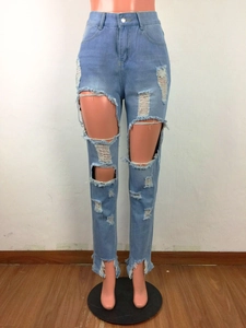 Détail de la texture déchirée et de l'ourlet effiloché sur un jean bleu clair délavé