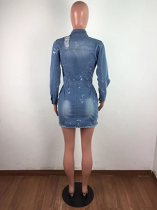 Detail of distressed denim dress featuring splattered ink print and frayed hem design