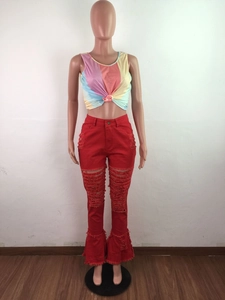 Detail of red distressed flare jeans with large ripped holes and frayed ruffle hem edges