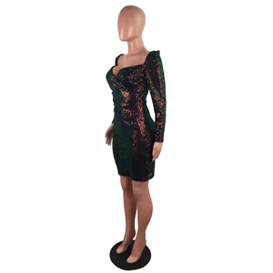 Détail d'une mini-robe à paillettes vert émeraude avec décolleté en cœur et manches