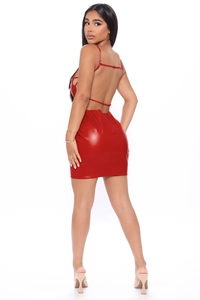 Dettaglio posteriore di un mini abito rosso in pelle PU con spalline incrociate e schiena nuda