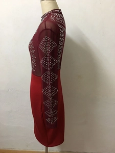 Detail of burgundy mesh sleeve with intricate rhinestone diamond patterns on party dress