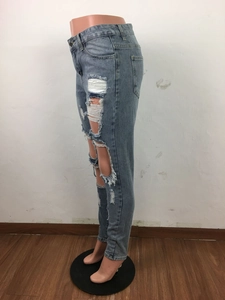 Dettaglio dei jeans in denim azzurro con strappi vistosi e bordi sfrangiati
