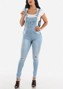 Distressed light blue denim overalls for women styled with a white short sleeve t-shirt