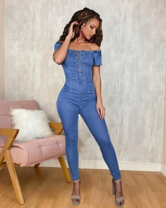 Detail of off-shoulder denim jumpsuit featuring lace-up drawstring and skinny fit design