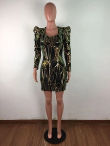 Détail des paillettes géométriques dorées et vertes sur la robe courte noire à col V