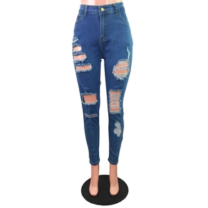 Détail de denim déchiré montrant le tissu effiloché et le bouton en métal sur jean slim