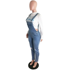 Detail of light blue distressed denim overalls with ripped knees and metallic buckles