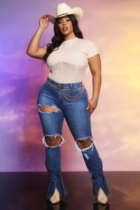 Dettaglio dei jeans in denim con ginocchia strappate e orlo svasato con spacco laterale