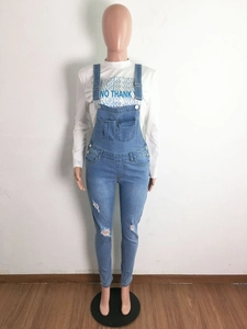 Detail of distressed light blue denim overalls with front pocket and ripped knee accents