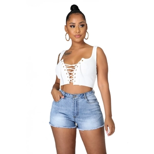 Détail d'un crop top blanc côtelé avec laçage à œillets et short en jean à bords effilochés