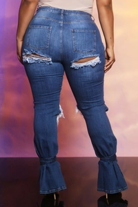 Dettaglio dei jeans in denim blu scuro con strappi e chiusura con lacci sul fondo
