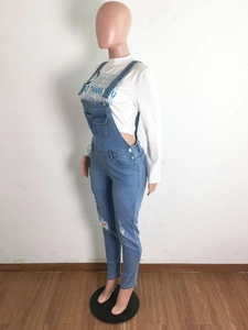 Detail of blue distressed denim overalls with knee holes and white long sleeve t-shirt